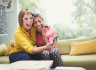 Lachende reife Frauen, die sich umarmen und Selfie auf dem Sofa machen — Stockfoto