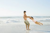 Pai balançando filha no surf na praia — Fotografia de Stock