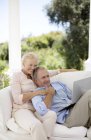 Senioren-Paar benutzt Laptop auf Terrassensofa — Stockfoto