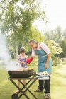 Grandfather and granddaughter grilling at barbecue in backyard — Stock Photo