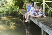 Родина відпочиває на пішохідному мосту над ставком — стокове фото