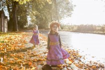 Toddler girls in Halloween costumes walking in autumn leaves — Stock Photo