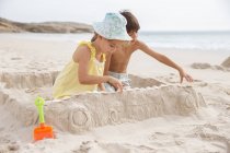 Дети делают песчаный замок на пляже — стоковое фото
