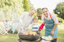 Homens de várias gerações grelhando carne e milho no churrasco no quintal — Fotografia de Stock