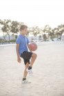 Garçon à genoux ballon de football dans le sable — Photo de stock