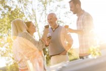 Casal de idosos e crianças adultas bebendo vinho no pátio ensolarado — Fotografia de Stock