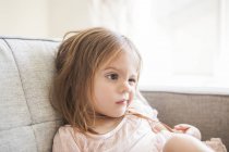 Toddler girl making a face on sofa — Stock Photo
