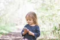 Menina criança usando telefone celular no parque — Fotografia de Stock