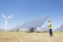 Operaio che esamina i pannelli solari nel paesaggio rurale — Foto stock