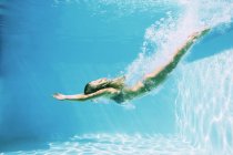 Vista lateral de la mujer buceando en la piscina - foto de stock