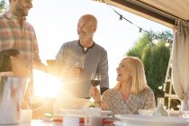 Família beber vinho na mesa do pátio ensolarado — Fotografia de Stock