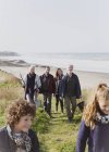 Родина багатьох поколінь, що йде сонячною травою на пляжній доріжці — стокове фото