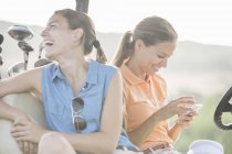 Mujeres jóvenes caucásicas sentadas en el carrito de golf - foto de stock