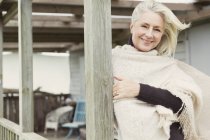 Porträt lächelnde Seniorin mit Schal auf windiger Veranda — Stockfoto
