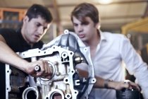 Mecânica examinando parte na oficina de reparação de automóveis — Fotografia de Stock