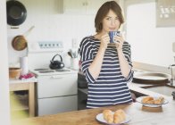 Brunette woman drinking coffee in kitchen — Stock Photo