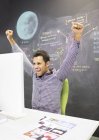Businessman cheering at desk in modern office — Stock Photo