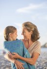 Older woman holding granddaughter on beach — Stock Photo