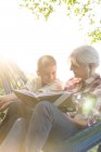 Бабуся читає онуку в сонячному гамаку — стокове фото