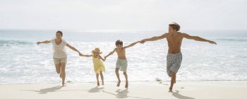 Família correndo juntos na praia — Fotografia de Stock