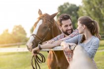Пара с лошадью разговаривают на сельском пастбище — стоковое фото