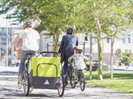 Семьи на велосипедах в солнечном городском парке — стоковое фото