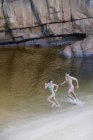 Paar läuft in See gegen Felsen — Stockfoto