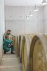 Vintners examining barrels in winery cellar — Stock Photo