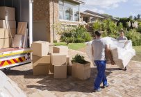 Movers carrying sofa from moving van to house — Stock Photo