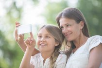 Мати і дочка використовують мобільний телефон на відкритому повітрі — стокове фото