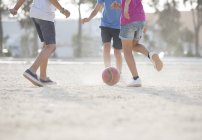 Children playing with soccer ball in sand — Stock Photo