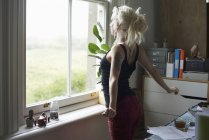 Junge Frau streckt sich am Fenster im Home Office — Stockfoto