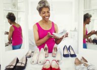 Smiling mature woman looking at high heels in closet — Stock Photo