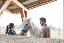 Couple petting horse in rural stable — Stock Photo