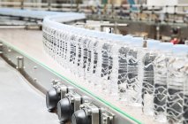 Botellas en cinta transportadora en fábrica - foto de stock