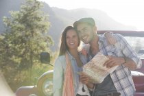 Lächelndes Paar mit Landkarte neben Sport Utility Vehicle — Stockfoto
