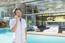 Man talking on cell phone at poolside — Stock Photo