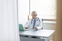 Doutor trabalhando no laptop no consultório do médico — Fotografia de Stock