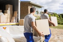 Movers carrying boxes in new house — Stock Photo