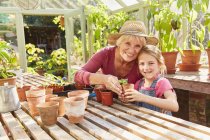 Портрет улыбающейся бабушки и внучки горшки растений в оранжерее — стоковое фото