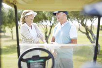 Старшая пара смеется на поле для гольфа — стоковое фото