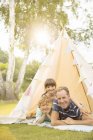 Father and children relaxing in teepee in backyard — Stock Photo