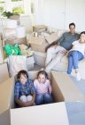 Brother and sister inside cardboard box in living room — Stock Photo