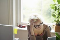 Стрессовая женщина с руками в волосах работает в офисе — стоковое фото