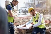 Trabajador de la construcción e ingeniero revisando planos en el sitio de construcción - foto de stock