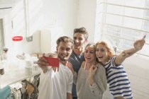 Enthusiastic young adult roommates taking selfie in kitchen — Stock Photo