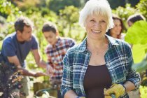 Portrait smiling senior woman in sunny garden with family — Stock Photo