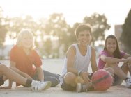 Niños con pelota de fútbol sentados al aire libre - foto de stock