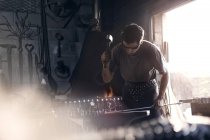 Blacksmith forging iron at anvil in forge — Stock Photo
