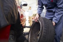 Mechanic replacing tire in auto repair shop — Stock Photo